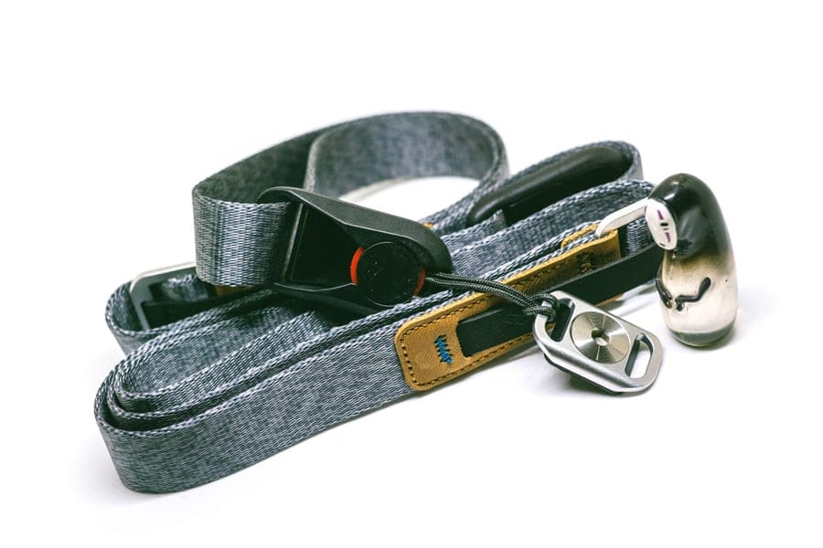 A small clip-on Bluetooth speaker hanging from a backpack strap