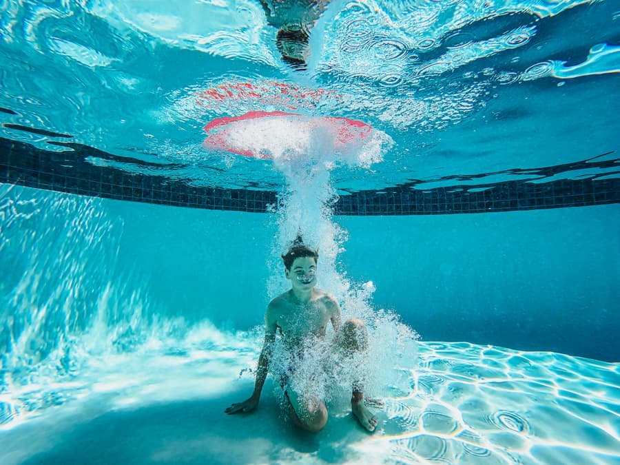 A round waterproof Bluetooth speaker floating at the edge of a pool