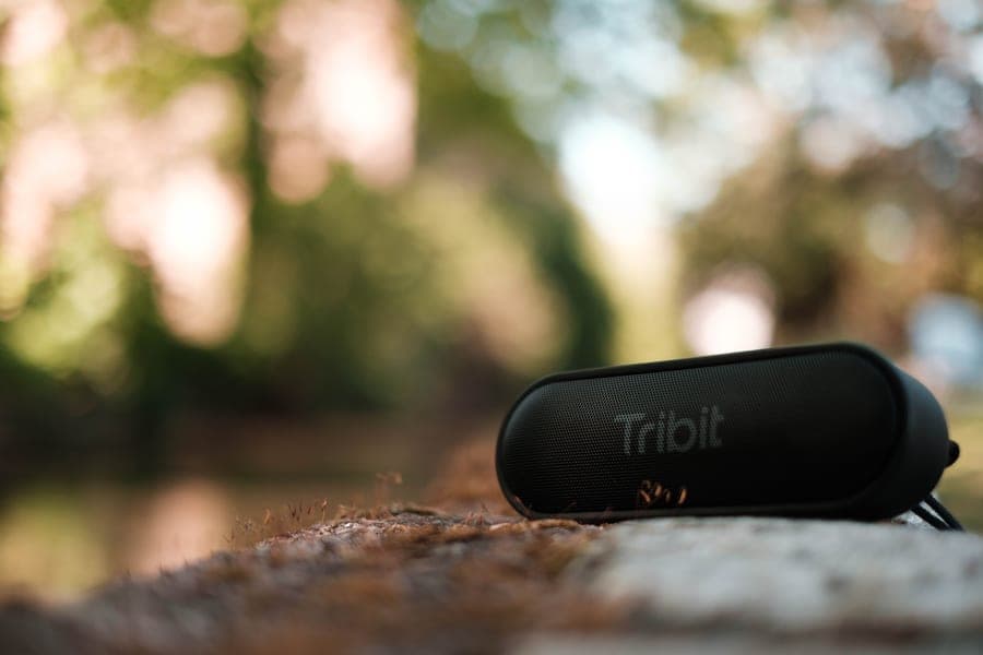 A larger cylindrical Bluetooth speaker on a picnic bench outdoors