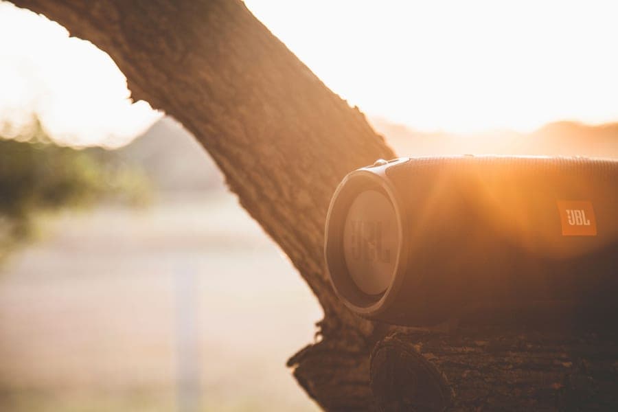 A compact portable Bluetooth speaker resting on a wooden outdoor table