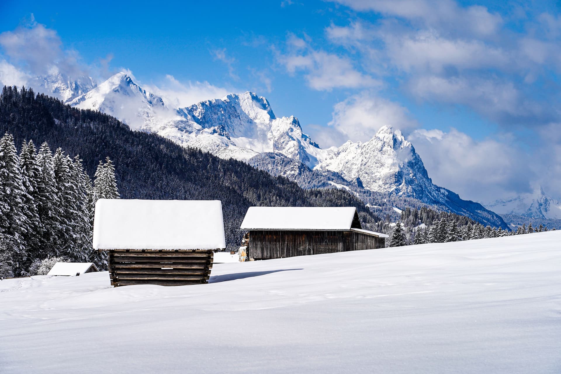 Snow-covered cabins below mountains in winter