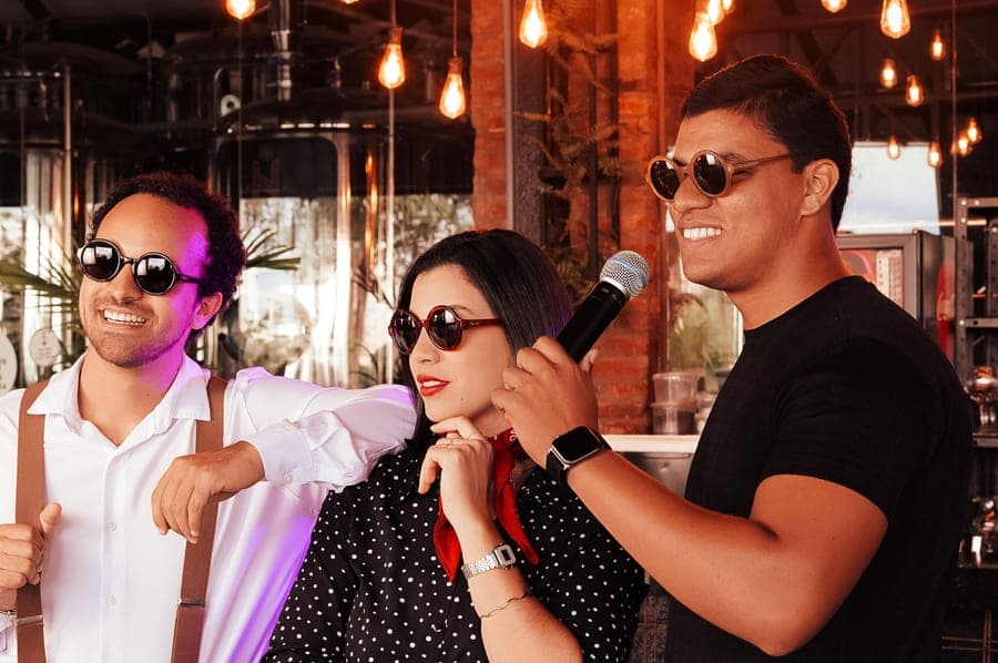 Three friends singing together at an indoor karaoke session