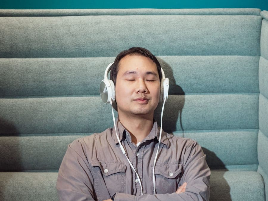 A man listening to music on headphones indoors with his eyes closed