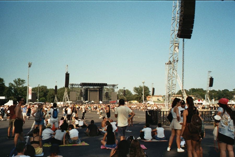 A crowd at an outdoor event with speakers running