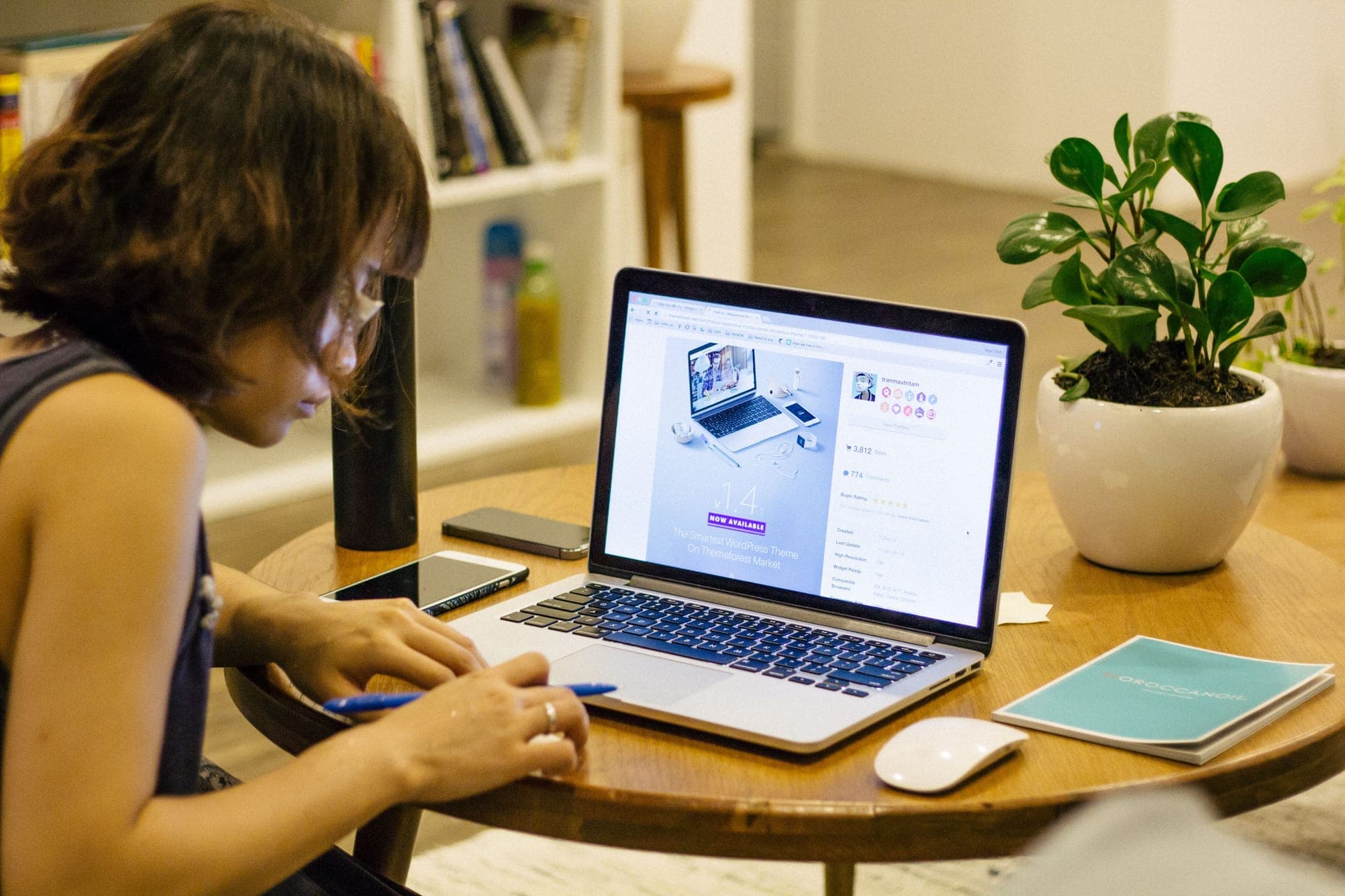 A person working at a home office desk with a laptop and a plant