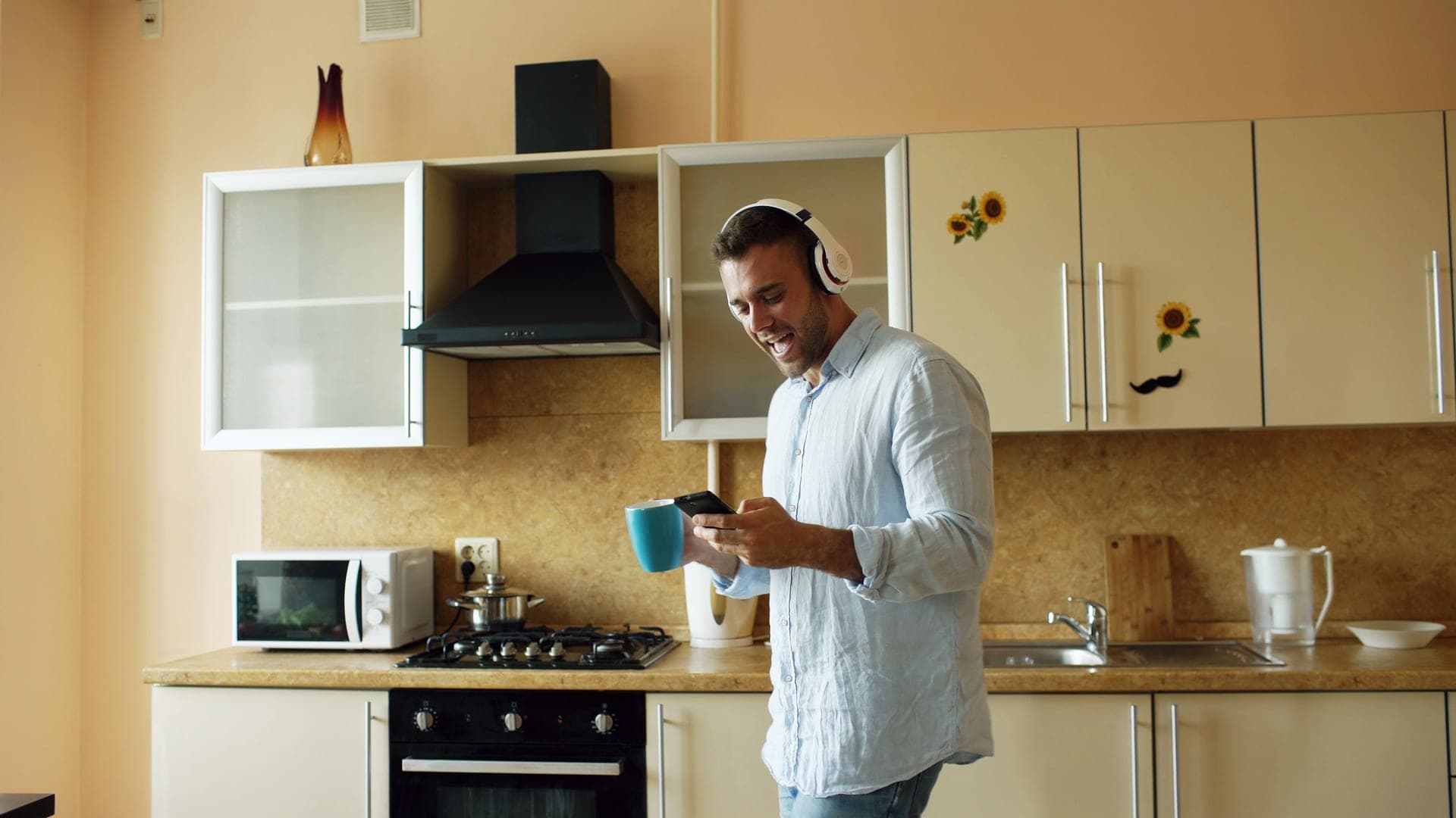 A man listening to audio at home while holding a mug