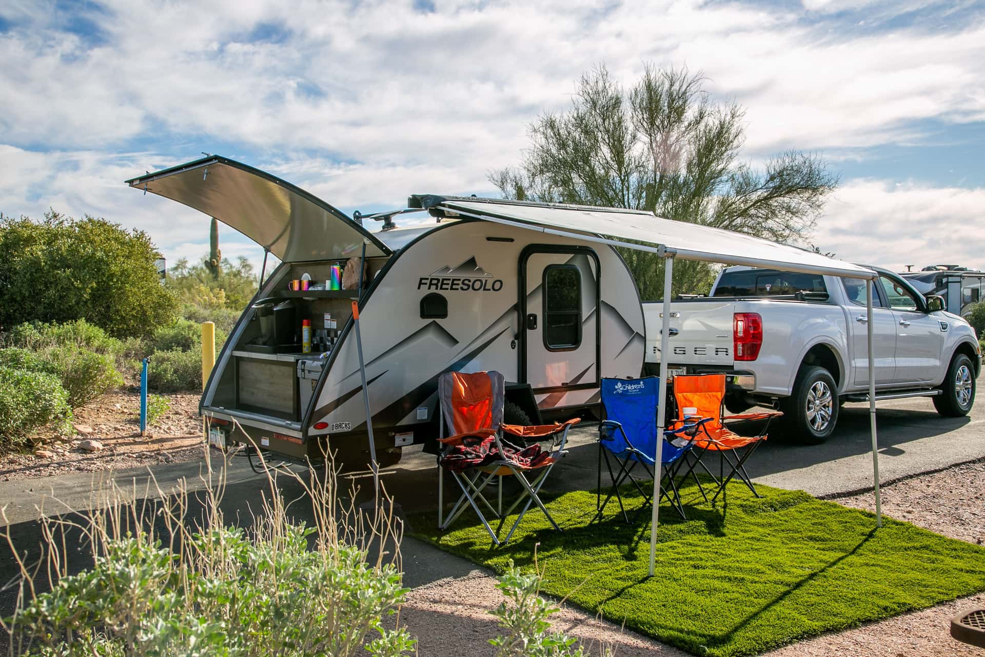 A motorhome parked at a desert campsite with camping chairs set out beside it