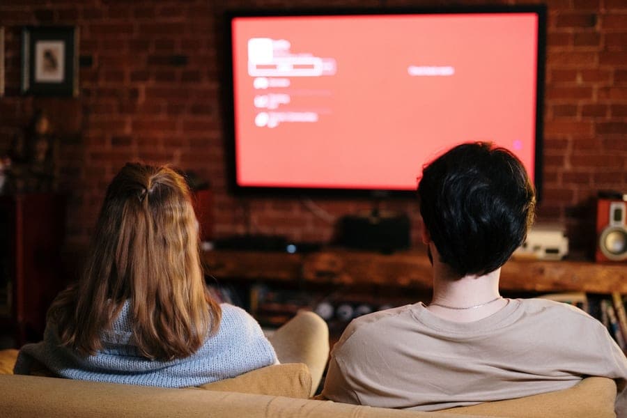 A couple watching television together in a cozy brick-walled living room